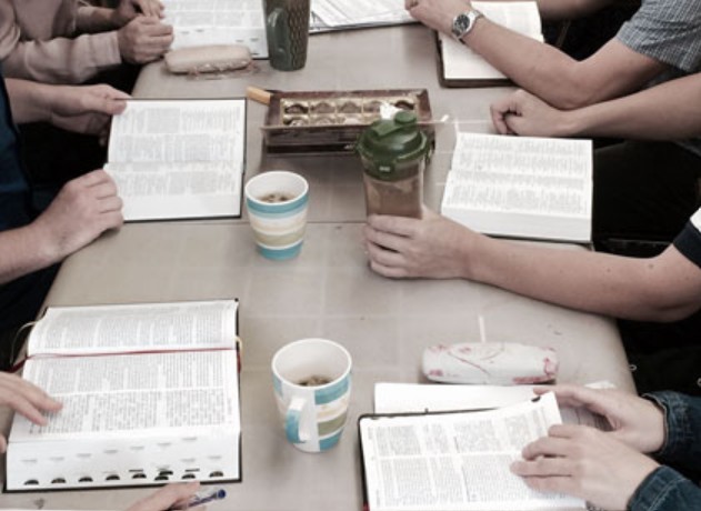 Open Bibles and coffee cups around a table at Tuesday evening Bible study